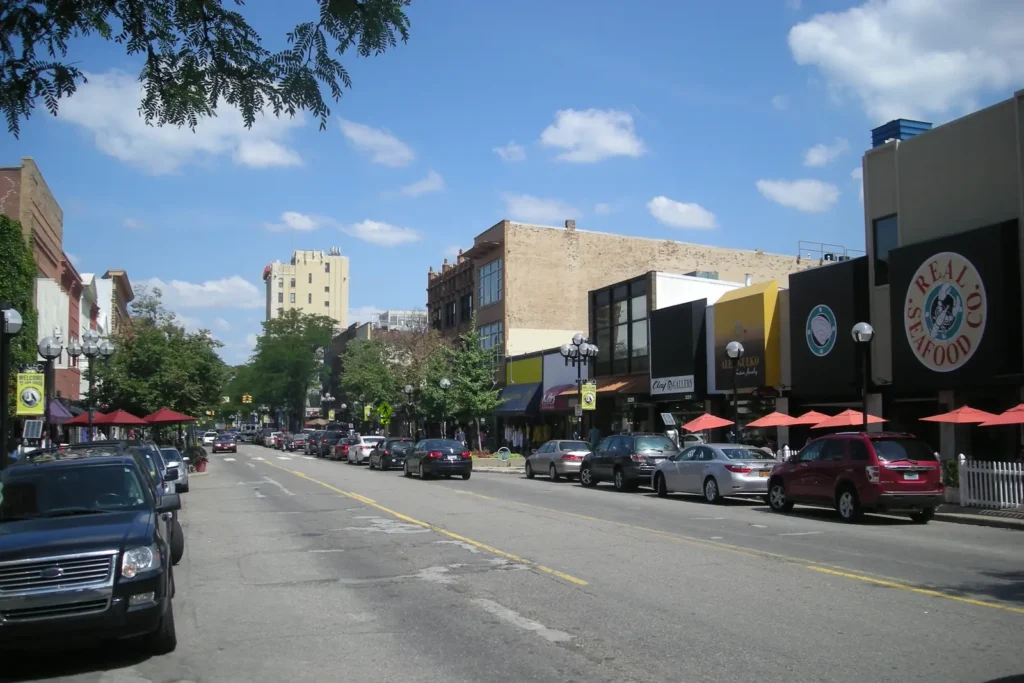 Storefronts, restaurants and parked cars along Main Street in downtown Ann Arbor on a sunny summer day