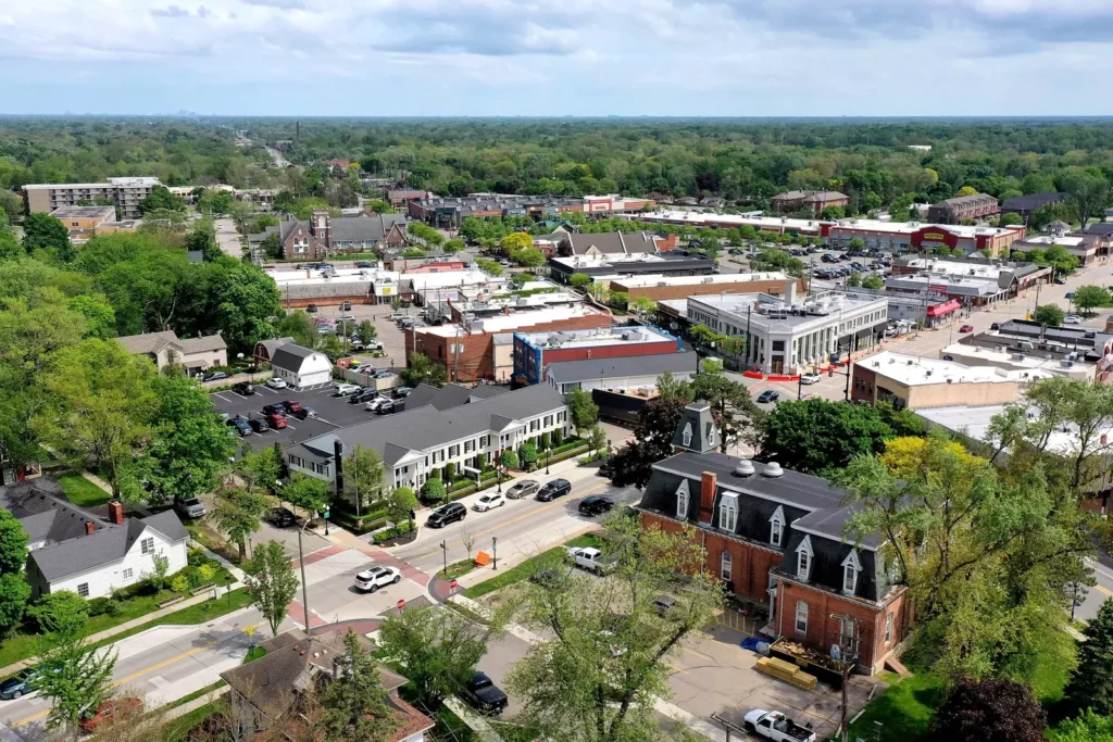 High view of downtown Farmington, Michigan in spring, with tree-lined streets, historic brick buildings and Grand River Avenue shops