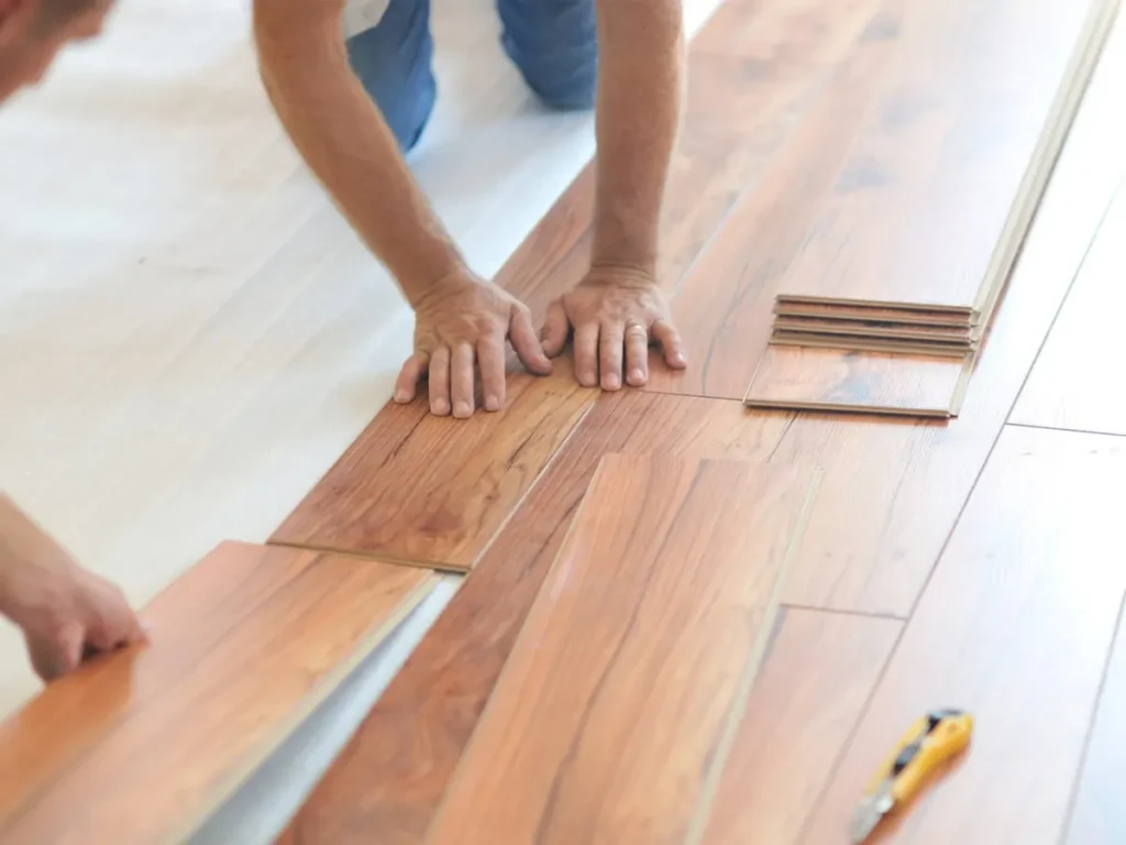 Installer's hands fitting hardwood floor planks into place