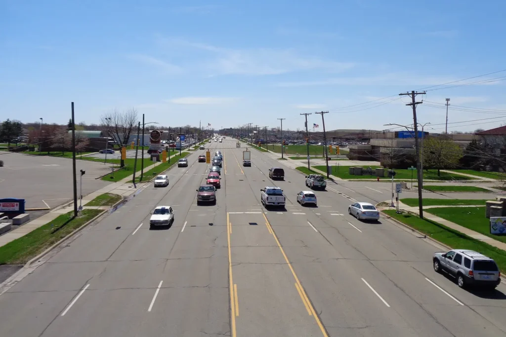 View from an overpass looking down Dix-Toledo Road in Southgate, Michigan, with traffic, shopping centers and retail signs on a sunny day
