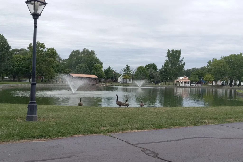 Coan Lake with two fountains and the historic village buildings in Heritage Park, Taylor, Michigan