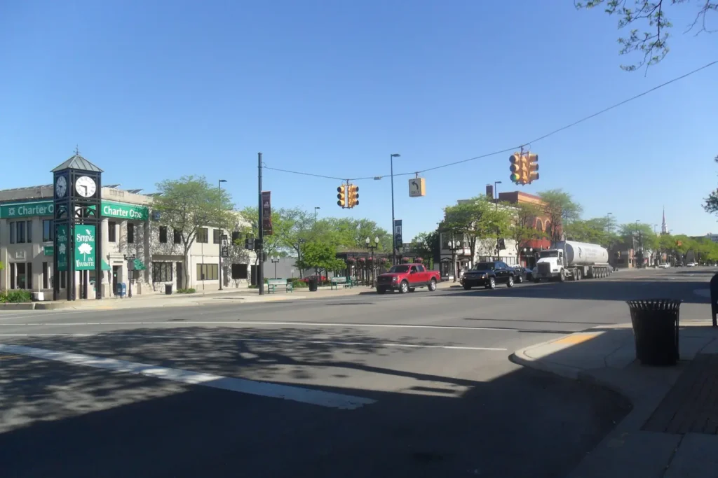 A street clock and two-story storefronts at a sunny intersection in downtown Wyandotte, Michigan